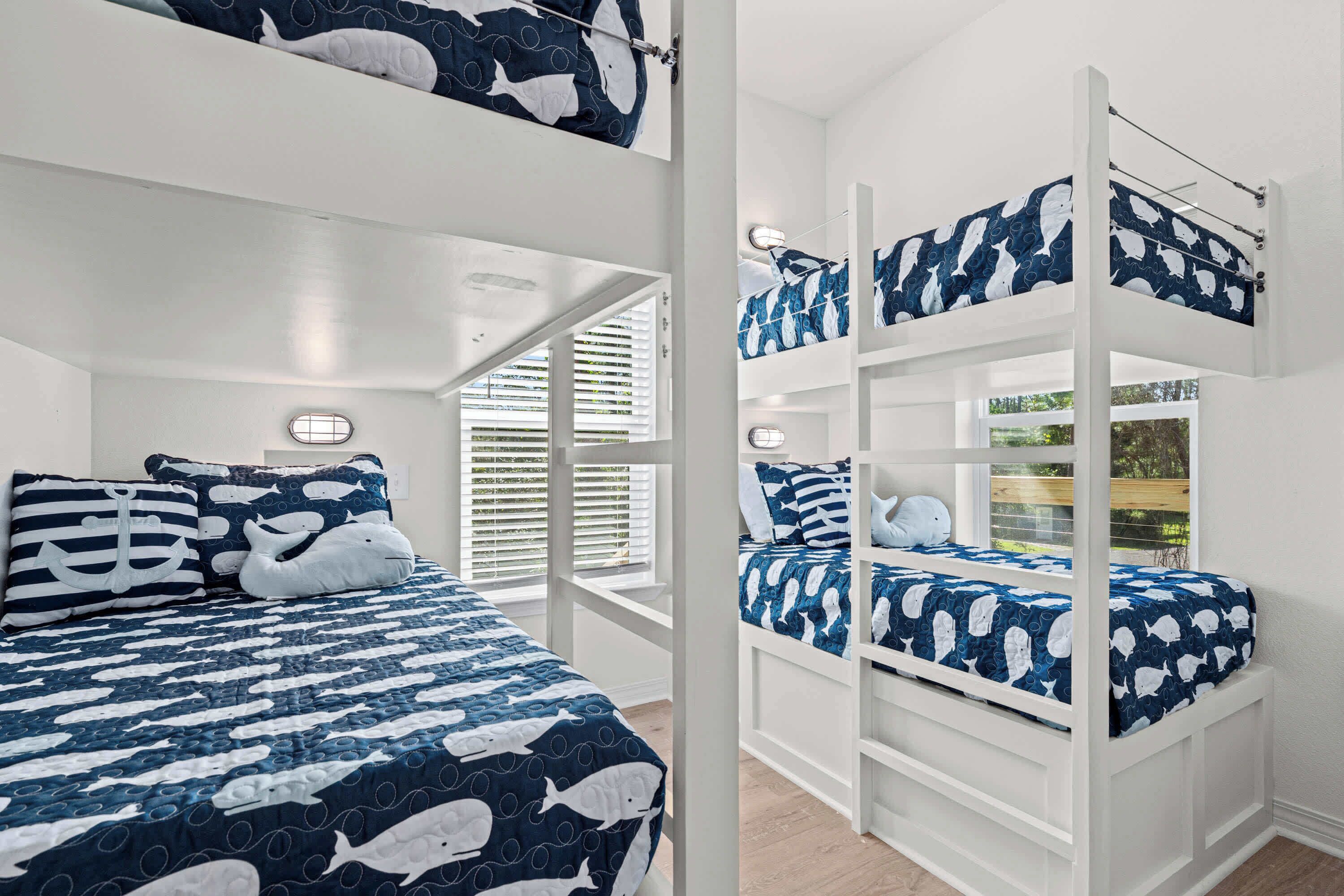 A bunk bed room with a nautical theme, featuring a blue and white color scheme and a window with blinds.