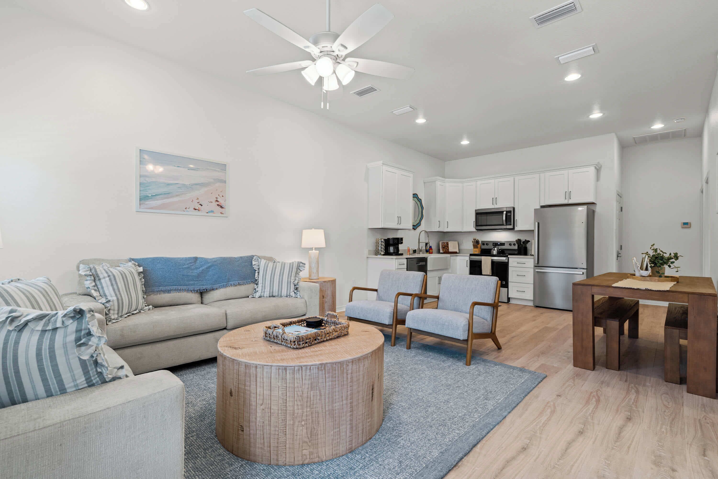 A modern living room with a sofa, armchairs, a coffee table, and a dining table.