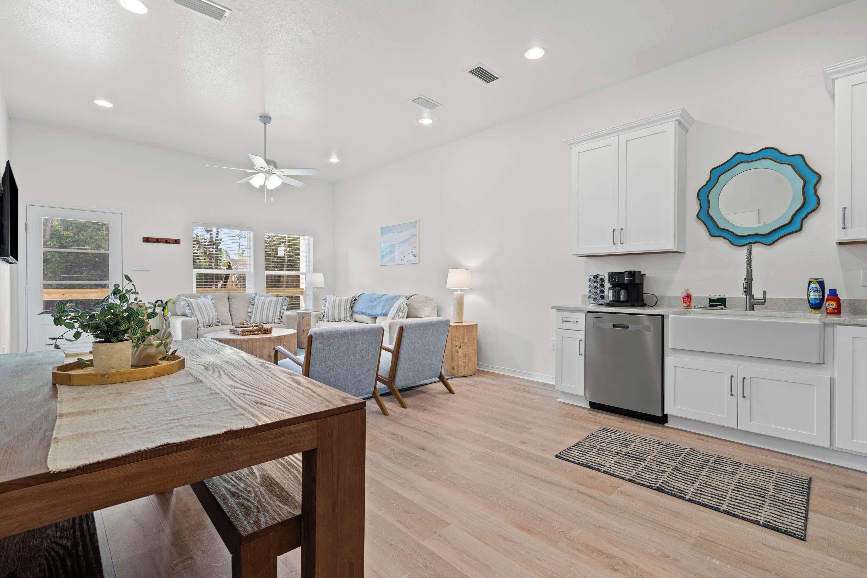 A modern kitchen with white cabinets, a dishwasher, and a blue-framed mirror.