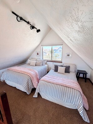 A bedroom with two beds, a window, and a ceiling fan.