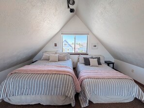 Ein Schlafzimmer mit zwei Betten, einem Fenster mit Aussicht und einer Deckenleuchte.