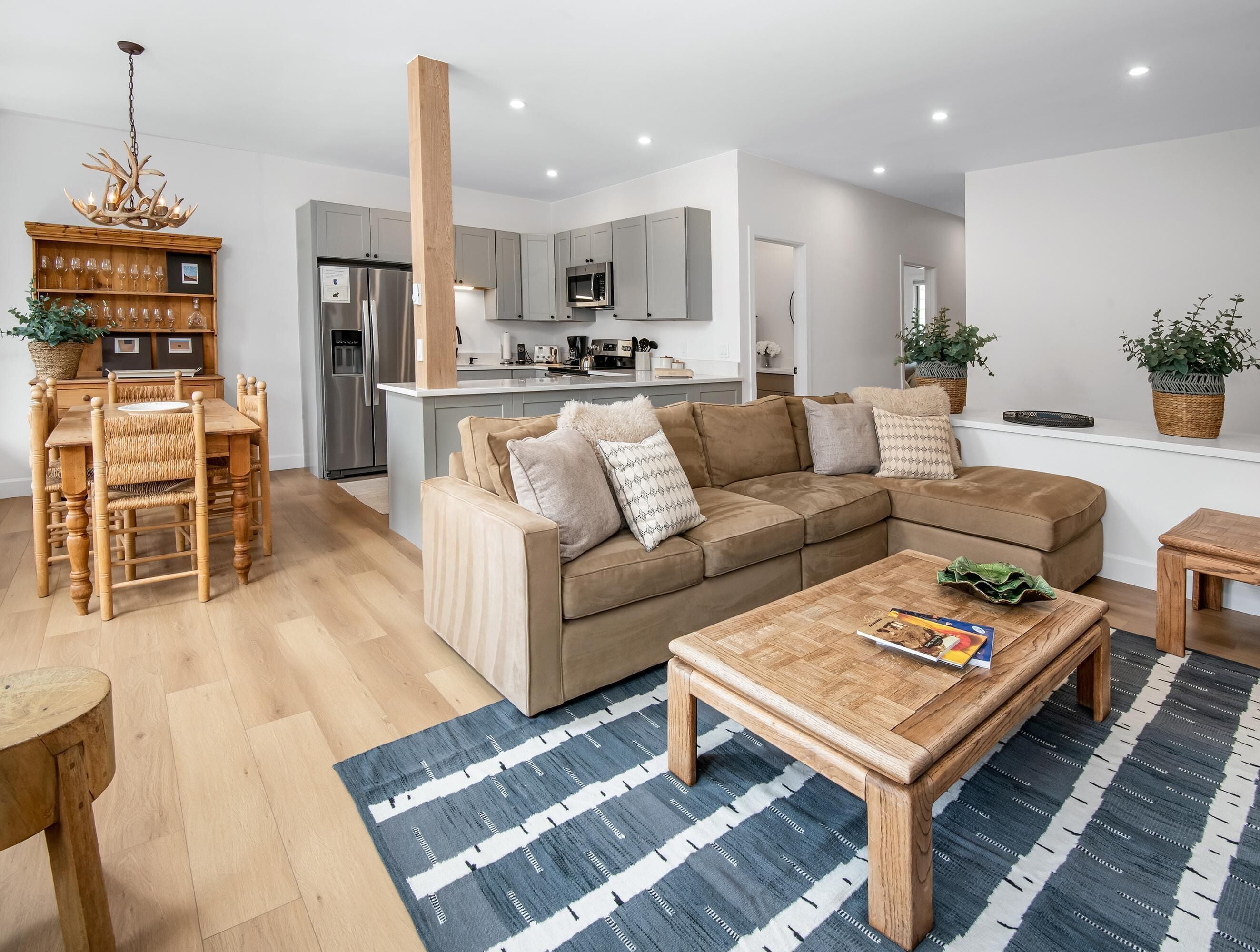Uma sala de estar moderna com sofá seccional, mesa de centro de madeira e área de jantar com mesa e cadeiras de madeira.