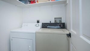 Una sala de lavandería con lavadora de carga frontal y secadora de carga superior.