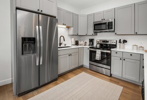 A modern kitchen with stainless steel appliances, grey cabinets, and a wooden floor. - Sun Vail 32b, 2BD Condo With Vail Mountain Views (Vail)
