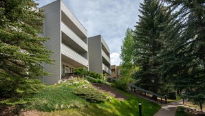 Un edificio moderno con techo plano, rodeado de árboles y un camino de ladrillo.