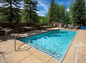 A rectangular swimming pool with a metal ladder, surrounded by stone tiles and a stone wall. - Sun Vail 32b, 2BD Condo With Vail Mountain Views (Vail)