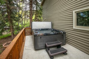 Ein Whirlpool mit Stufen, eine Holzterrasse und ein Haus mit Verkleidung.