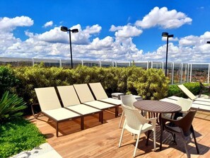 A rooftop terrace with lounge chairs, a round table, and a view of the cityscape. - Apartamento completo, próximo ao aeroporto de Guarulhos - Via alameda (Guarulhos)
