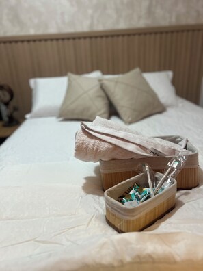 A neatly made bed with pillows, a small wooden basket with toiletries, and a folded towel on the bed. - Apartamento completo, próximo ao aeroporto de Guarulhos - Via alameda (Guarulhos)