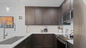 Eine moderne Küche mit dunklen Holzschränken, Edelstahlgeräten und einer weißen Arbeitsplatte.