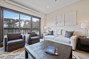 A modern living room with a sofa, armchairs, a coffee table, and large windows offering a view of a snowy landscape. - Borders Lodge U306 2BD Beaver Creek Ski-in, Ski-out Condo (Avon)