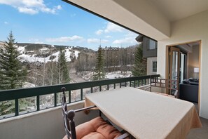 Ein Balkon mit Tisch und Stuhl mit Blick auf eine verschneite Berglandschaft.