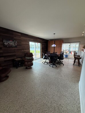 Ein geräumiges Zimmer mit Esstisch, Stühlen, einer Sitzecke und Blick ins Freie.