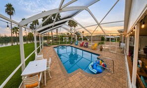 Piscina ao ar livre coberta com espreguiçadeiras e área de churrasco.