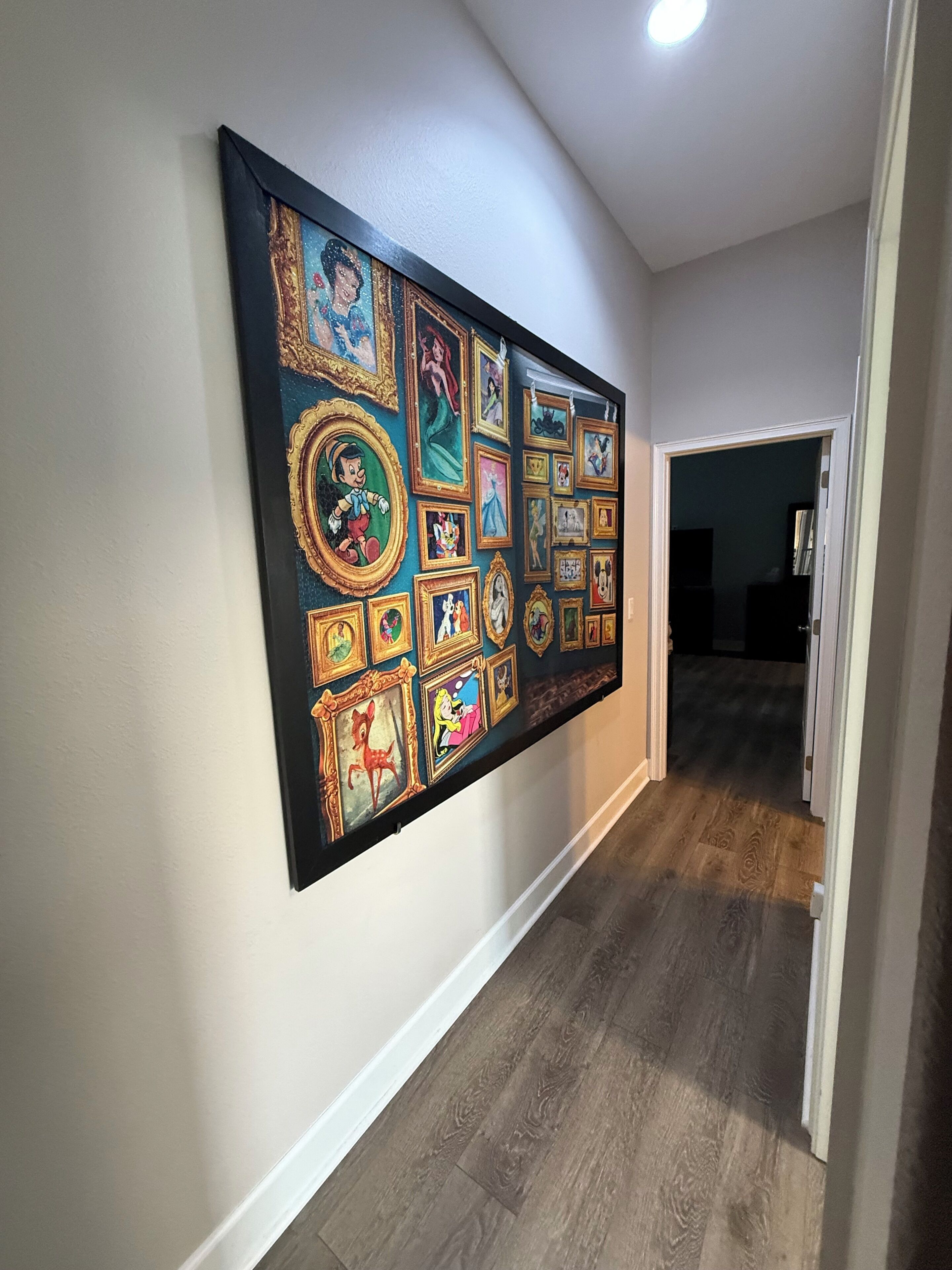 A hallway with a wall-mounted art display featuring various framed pictures.