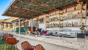 A bar area with a counter, bar stools, and shelves of bottles. - Morgan Residences 603 at Boutique Hotel With Pool, Gym & Spa (Cabo San Lucas)