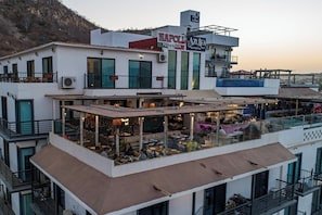 Un immeuble à plusieurs étages abritant un restaurant au rez-de-chaussée, un bar à l’étage supérieur et une terrasse sur le toit.