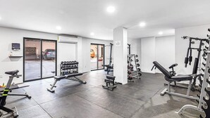 A gym with various exercise equipment, a treadmill, and a bench press. - Morgan Residences 603 at Boutique Hotel With Pool, Gym & Spa (Cabo San Lucas)