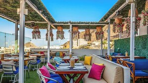 An outdoor dining area with tables and chairs, a sofa, and hanging decorations. - Morgan Residences 603 at Boutique Hotel With Pool, Gym & Spa (Cabo San Lucas)
