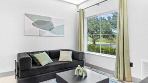 Ein modernes Wohnzimmer mit einer Couch, einem Couchtisch und einem Fenster mit Vorhängen.
