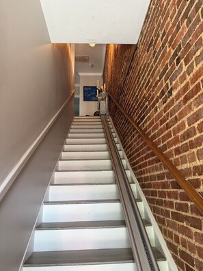 A staircase with a glass railing, a brick wall, and a sign that reads 'HOME Sweet HOME'.