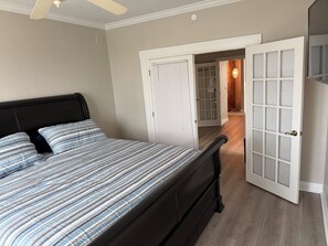 A bedroom with a bed, a ceiling fan, and a door leading to a hallway. - Spacious 3-bedroom apartment in the heart of charming Historic Clermont (Clermont)