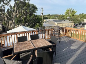 A deck with outdoor furniture, a view of a residential area, and a covered structure in the background. - Spacious 3-bedroom apartment in the heart of charming Historic Clermont (Clermont)