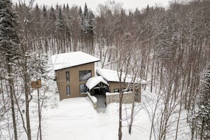 A modern two-story cabin with a snow-covered roof, surrounded by a forest. - Le Miléna | Private SPA & Sauna | Billiards & Pool (Les Laurentides Regional County Municipality)