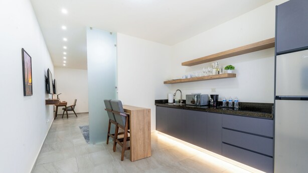 A modern kitchen with a built-in island, dark cabinetry, and a stainless steel refrigerator. - Bella Terra (Hermosillo)