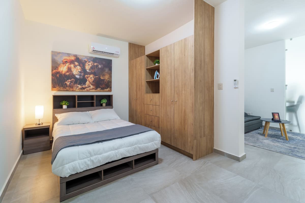 Une chambre à coucher avec un lit, des tables de chevet, une armoire en bois et un tableau accroché au mur.