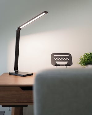 A desk with a modern desk lamp, a wall-mounted light switch, and a small potted plant. - Bella Terra (Hermosillo)