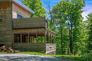 Une cabane en bois avec un porche, entourée d’arbres.