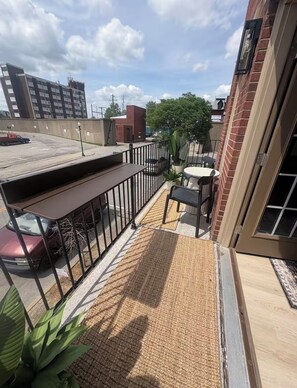 A rooftop patio with a table and chairs, a small garden area, and a view of the cityscape. - River View Townhome w/ Balcony • 2BR • Sleeps 6 (Jeffersonville)