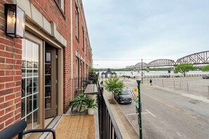 Un bâtiment en briques doté d’un balcon, donnant sur la rue, avec un pont visible au loin.