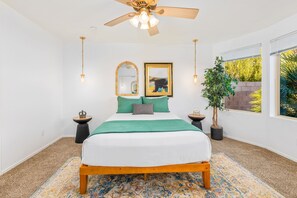 A bedroom with a bed, a ceiling fan, a large window, and a potted plant. - Secluded Retreat: Private, Beautiful Home Wow (Tucson)