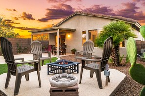 Una veranda esterna con quattro poltrone Adirondack, un braciere e un tavolino.