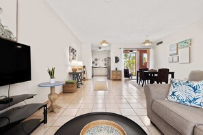 Ein Wohnzimmer mit Fernseher, Sofa und Essbereich.