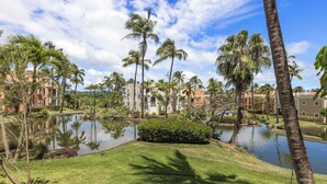 A residential area with a pond, palm trees, and buildings. - Peaceful Waterfalls Luxury 2BR (FC872) (Humacao)