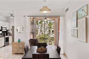 Eine moderne Küche mit Essbereich, Deckenventilator und Blick durch eine Glastür.