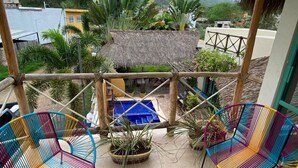 Un espace extérieur abrité comprenant deux chaises colorées, une petite piscine et une vue sur un bâtiment à toit de chaume et sur la verdure.