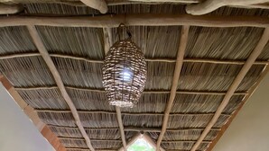 A room with a thatched ceiling, a hanging light fixture, a staircase with a metal railing, and a window with curtains. - Casa Tropical Nibasan, beautiful garden and swimming pool (San Francisco)