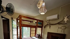 Une chambre avec un lit superposé, une table de chevet, un luminaire suspendu et une fenêtre donnant sur un beau paysage.