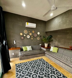 A modern living room with a grey sofa, a patterned rug, and wall decor. - Casa Tropical Nibasan, beautiful garden and swimming pool (San Francisco)