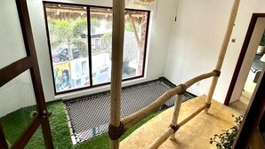 Une pièce avec un escalier en bois, un ventilateur de plafond et une fenêtre donnant sur la rue.