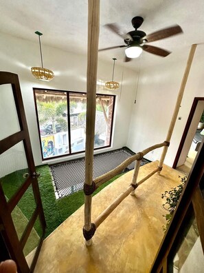Ein Zimmer mit einer Holztreppe, einem Deckenventilator und einem Fenster mit Blick auf die Straße.