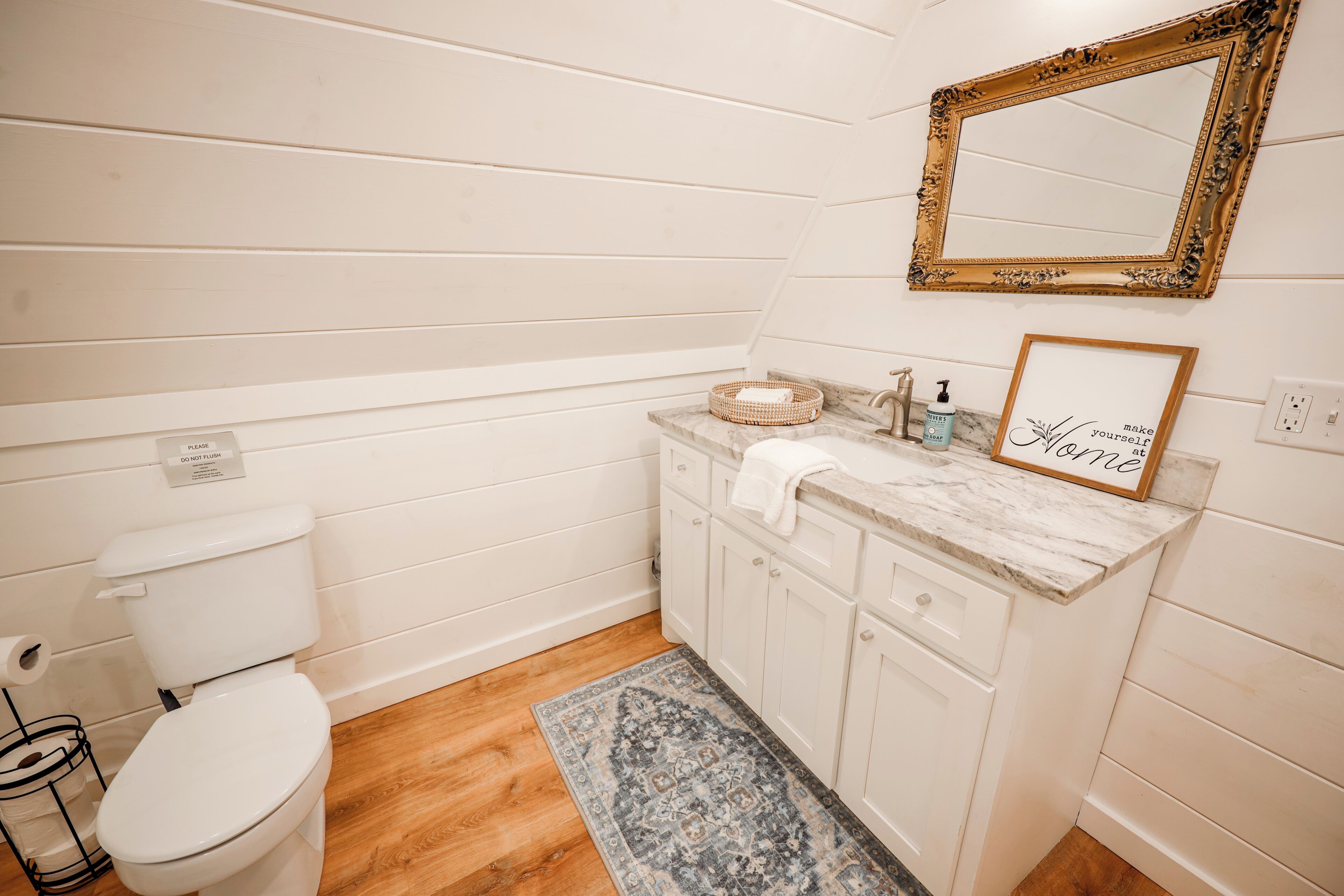 A bathroom with a white toilet, marble sink, and a framed mirror.