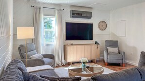 Een woonkamer met een bank, fauteuils, een salontafel, een televisie en een klok.