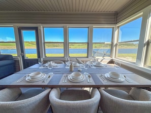 Mesa de jantar posta para quatro com vista para um lago e campos.
