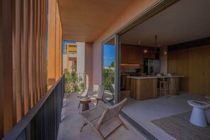 A modern kitchen with a bar area, a balcony with seating, and a view of the outdoors. - 1BR Penthouse in Aflora condo w/ Private Pool (Tulum)