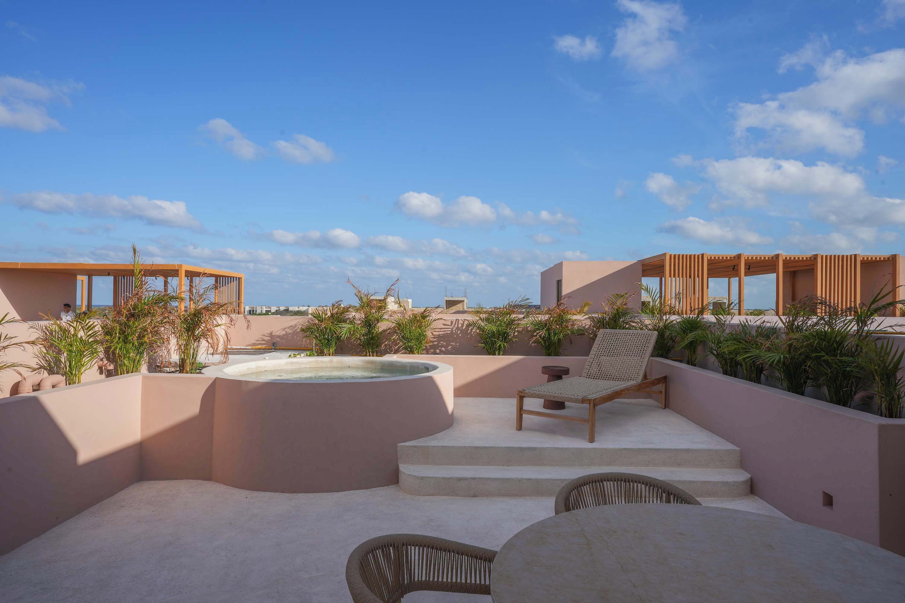 An outdoor patio area with a hot tub, lounge chairs, and steps leading to a pool.